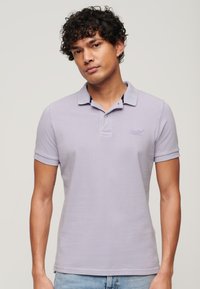 Lichtpaarse polo met korte mouwen, kraag en een sluiting met twee knopen; voorzien van een geborduurd logo op de borst.