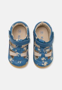 Sininen nahkainen vauvan sandaalit, joissa on valkoinen kukkakuva, tarranauha, avoin muotoilu ja beige yksityiskohta ylhäällä ja pohjassa. Koko 18.