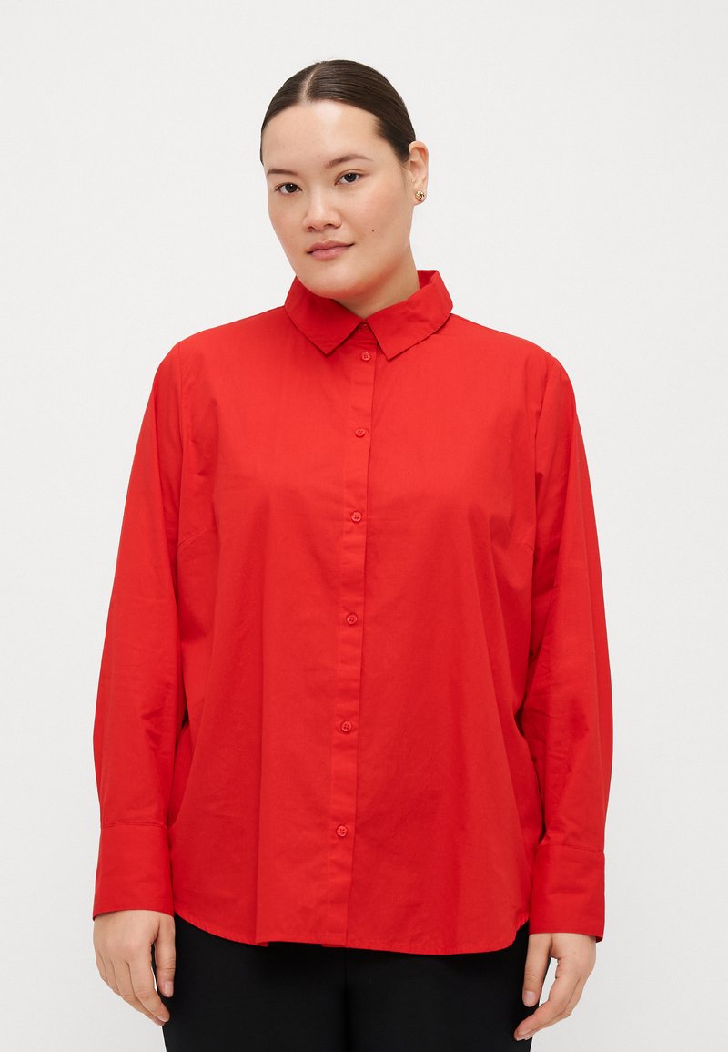 Camicia rossa con bottoni, colletto classico, maniche lunghe e vestibilità ampia. Tessuto liscio senza motivi o dettagli visibili.