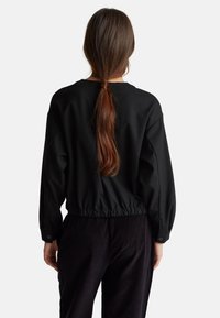 Černý zkrácený svetr s balónovými rukávy, elastickým pasem a knoflíkovými manžetami. Hladká tkanina, jednoduchý design, bez vzorů a akcentů.