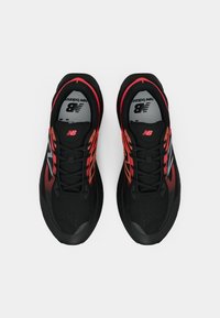 Svarte atletiske sko med røde detaljer og grått design. Har mesh-overdel, rund tå og snøresystem for sikker passform.