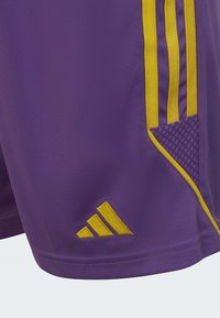 Lila Sportshorts mit gelben Drei-Streifen-Design, Netzpaneel und gesticktem Logo am Saum. Glattes, atmungsaktives Material.