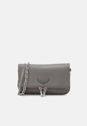 Grå lær crossbody-veske med kjedesnor, med klaffelukking, metallisk detaljering og dekorativ vingeemblem på forsiden.