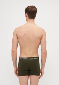 Olivgrüne Boxershorts mit einem schwarzen Bund, der weißen Markentext aufweist. Glattes Material, körperbetonter Schnitt und kurzes Bein-Design.