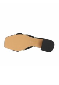 Scarpa nera con tacco alto e suola testurizzata, con interno beige liscio, punta arrotondata e sottile cinturino alla caviglia con dettagli in argento.