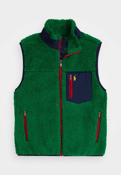 Πράσινο fleece γιλέκο με ψηλό γιακά, ναυτικές υφασμάτινες λεπτομέρειες, κόκκινες φερμουάρ και τσέπη στο στήθος με ένα μικρό κίτρινο λογότυπο.