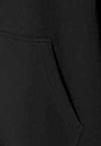 Svart sweatshirtmaterial med en texturerad yta. Har en framficka och synlig sömnad. Enkelt, funktionellt design.