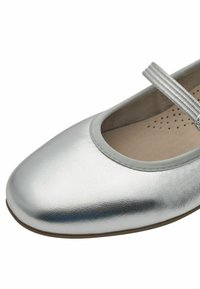 Zilveren flatschoenen met een ronde neus, een gladde metallic leren buitenkant en een zachte grijze voering. Voorzien van een platte elastische band over de wreef.