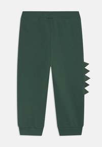 Joggers in cotone verde con vita elastica e polsini a coste, caratterizzati da un accento testurizzato simile a squame lungo il lato.