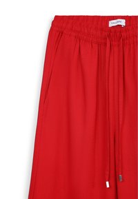 Rote Jogginghose mit Kordelzug und elastischem Bund, featuring eine glatte Textur und dezenten Glanz, akzentuiert durch silberfarbene Beschläge an den Kordeln.