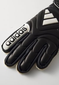 Svart målmannhanske med teksturert overflate, hvit Adidas-logo og polstring langs fingrene og baksiden for grep og beskyttelse.