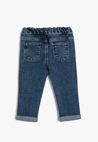 Vaqueros de mezclilla de color azul oscuro, con cintura elástica, dos bolsillos traseros y puños enrollados. Textura suave con detalles de costura visibles.