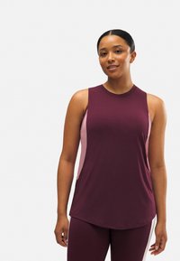 Top de entrenamiento sin mangas en color burdeos oscuro con paneles laterales en rosa claro. Tejido suave, dobladillo redondeado y ajuste atlético. Textura lisa, con un detalle mínimo.