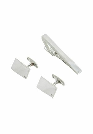 Silberne rechteckige Manschettenknöpfe und passende Krawattenklammer, jeweils mit einem kleinen klaren Stein an einer Ecke, isoliert auf weißem Hintergrund.