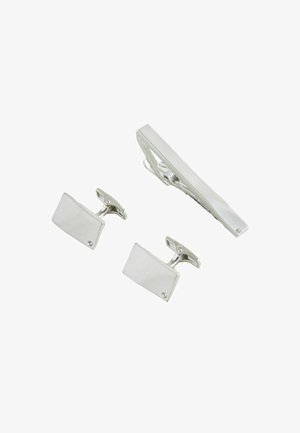 Silberne rechteckige Manschettenknöpfe und passende Krawattenklammer, jeweils mit einem kleinen klaren Stein an einer Ecke, isoliert auf weißem Hintergrund.