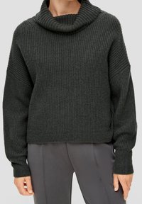 Ciemnozielony sweter z dzianiny, z kołnierzem typu cowl, prążkowaną fakturą i opadłymi ramionami. Posiada luźny krój i prosty dół.