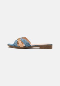 Blue denim slide sandals with a tan leather strap, gold accent hardware, flat sole, and textured upper.