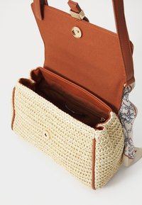 Woven straw handbag with a tan leather trim, featuring a magnetic closure and an interior pocket. Includes a patterned fabric accent.