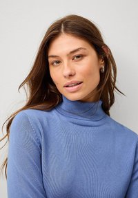 Lichtblauwe turtleneck trui van een zacht, textuurgebreid materiaal, met een aansluitende pasvorm en ribbelafwerking bij de kraag.