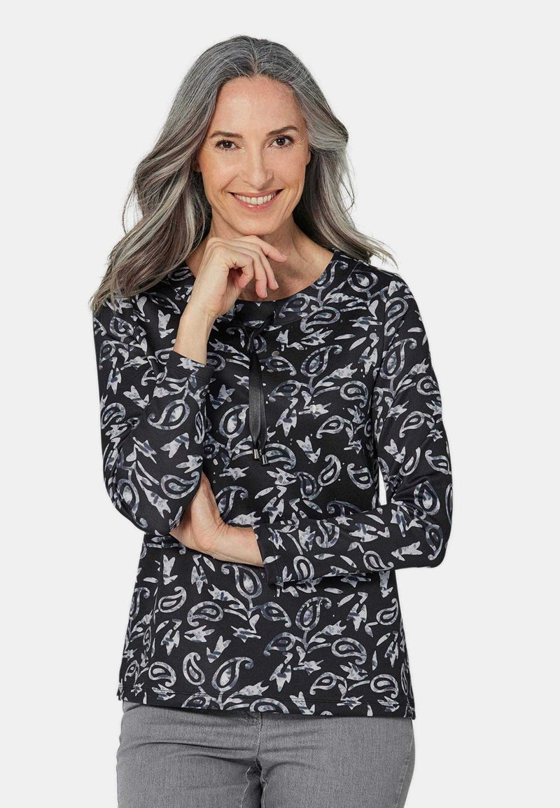 Langsleeve top met een zwarte basis, voorzien van een bloemen- en abstract patroon in grijs- en blauwtinten. Ronde halslijn met een strikdetail.