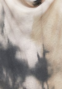 Tessuto con motivo astratto tie-dye in tonalità beige, nero e grigio, che mostra morbide pieghe e una texture liscia.