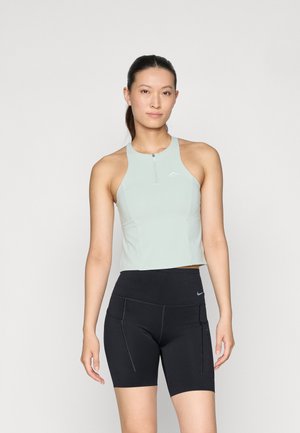 Vaaleanvihreä urheilullinen crop top, jossa on edessä vetoketju ja hihaton muotoilu, yhdistettynä mustiin istuviin shortseihin, joissa on sivutaskut ja kontrastitikkaukset.