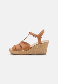Sandales à plateforme en cuir tan avec des brides entrecroisées, une bride à la cheville avec boucle, et une semelle à texture tissée.