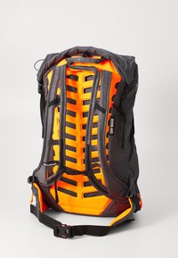 Sac à dos de randonnée avec un panneau arrière respirant orange vif, des bretelles rembourrées, une boucle de poitrine et une ceinture de taille ajustable sur fond uni.