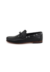 Schwarze Leder-Mokassinschuhe mit runder Zehenform, dekorativer Naht, seitlichen Ösen und einer niederen Profilsohle aus braunem Gummi.