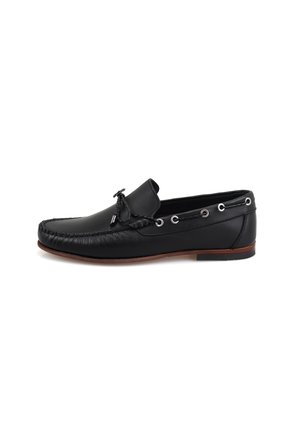 Mocassin en cuir noir avec un bout arrondi, couture décorative, œillets sur les côtés et semelle en caoutchouc brun à profil bas.