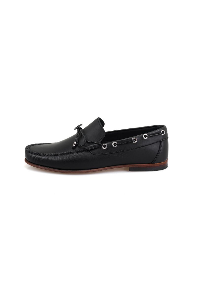 Schwarze Leder-Mokassinschuhe mit runder Zehenform, dekorativer Naht, seitlichen Ösen und einer niederen Profilsohle aus braunem Gummi.