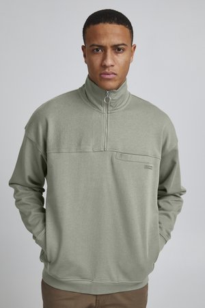 Light green fleece half-zip pullover with a pocket; features a raised collar and long sleeves. Simple, unembellished design.