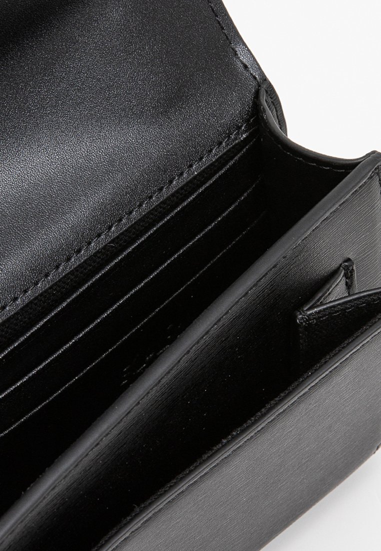 Portefeuille en cuir noir avec plusieurs emplacements pour cartes et un intérieur élégant. Texture lisse avec un design structuré et des détails matériels minimaux.