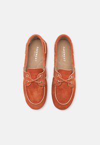 Scarpe da barca in suede arancione con punta rotonda, dettaglio con lacci e cuciture a contrasto. L'interno presenta un soletta con marchio su sfondo beige.
