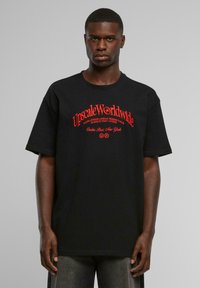Black cotton t-shirt with loose fit, short sleeves, and red graphic text. Features phrases "Upscale Worldwide" and "Casha Paris New York."