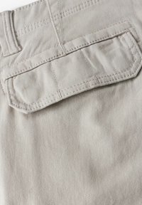 Tela gris claro con una textura suave, que presenta un bolsillo trasero con solapa rectangular y acentos cosidos para mayor durabilidad.
