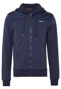 Sudadera navy con cremallera frontal, cordón y paneles de hombro en contraste. Presenta puños y dobladillo acanalados, hecha de una tela suave y texturizada.