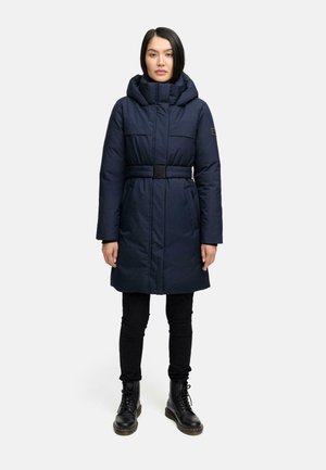 Dunkelblauer Puffer-Mantel mit Kapuze und tailliertem Design; verfügt über zwei seitliche Taschen und eine glatte Textur. Schwarze enge Hose und Stiefel runden das Outfit ab.
