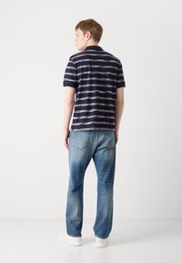 Mørkeblå stripete polo skjorte med korte ermer, parret med lyseblå denimjeans. Stripene har vekslende hvit og lys grå.