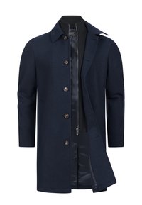 Manteau en laine bleu marine pour homme avec fermeture à boutons, associé à une couche intérieure noire zippée et un col à revers.