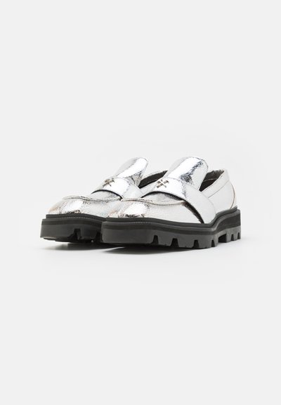 Silberne metallic Loafers mit strukturierter Oberfläche, kontrastierenden schwarzen robusten Sohlen und einem Kreuzstichakzent im oberen Bereich.