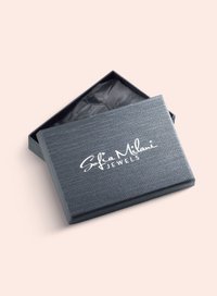 Grå rektangulær smykkeboks med en tekstureret overflade, der har et hvidt logo "Sofia Milani JEWELS" på toppen og sort indre beklædning.