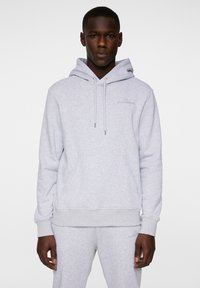 Ljusgrå hoodie i mjukt tyg, med en framficka, justerbar dragkedja på huvan och logotypdetalj på bröstet.