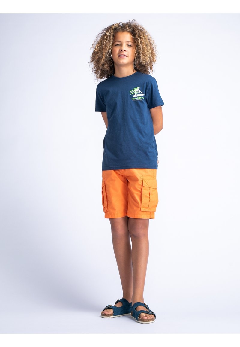 Marineblauw katoenen T-shirt met een groene grafische opdruk op de borst, gecombineerd met oranje cargoshorts en teal sandalen met een gespsluiting.