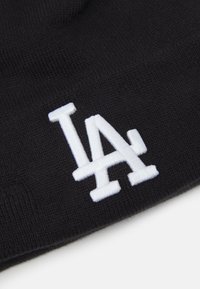 Berretto a maglia nero con logo "LA" ricamato in bianco. Texture morbida, design aderente e stile semplice. Nessun ornamento aggiuntivo.