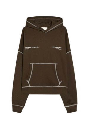 Sweat à capuche marron foncé avec coutures contrastantes blanches et texte à l'avant indiquant "Glow different — be the vibe you seek" et "and let the world enjoy it with you."