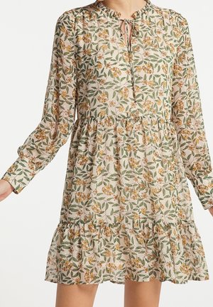 Robe beige à manches longues avec imprimé de feuilles vertes et fleurs jaunes, encolure en forme de trou avec lien, taille froncée et ourlet volanté.