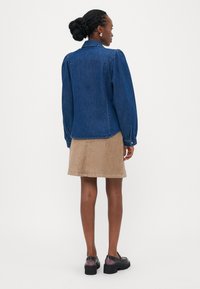 Denim skjorte med lange ermer og rett fasong, med puffede skuldre, knapp mansjetter og klassisk krage, kombinert med et beige kordfløyelskjørt.