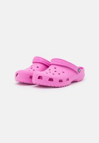 Pink Crocs clogs made of synthetic material, featuring ventilation holes, a back strap, and a textured sole for grip.