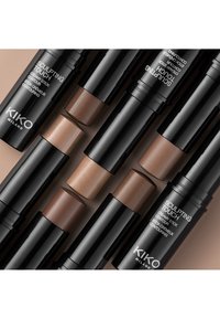 Set med KIKO Milano Sculpting Touch-krämstift i olika nyanser. Cylindrisk svart förpackning med färgkodade lock. Mjuk textur.